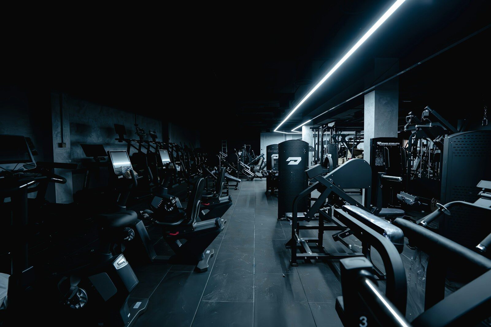 Dark gym interior with exercise equipment and weight machines.