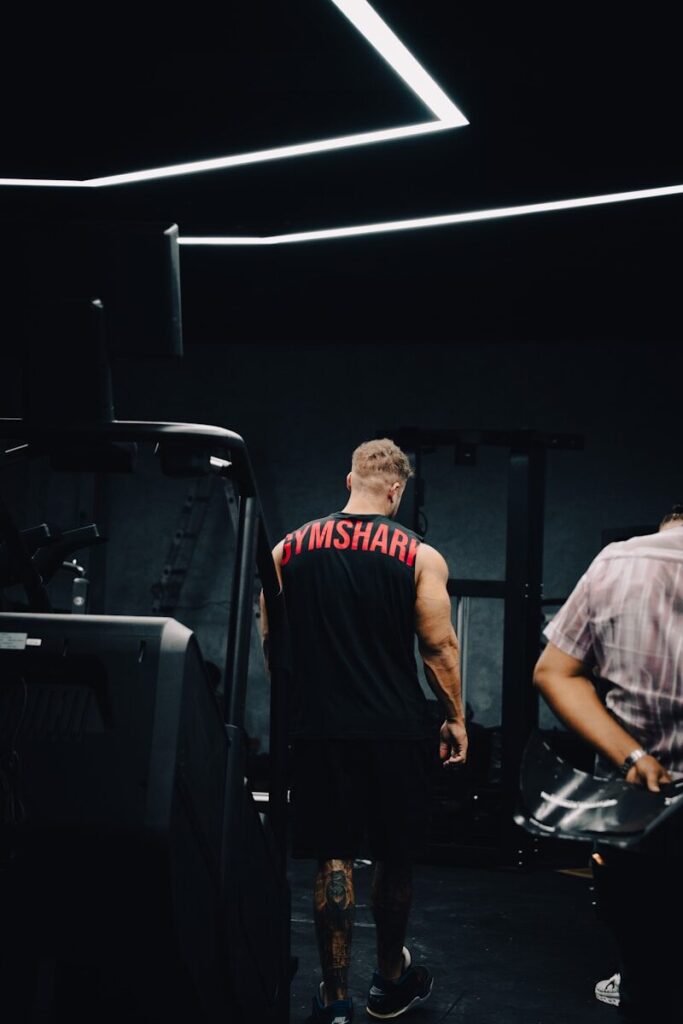 Man in gymshark shirt walks in dark gym.